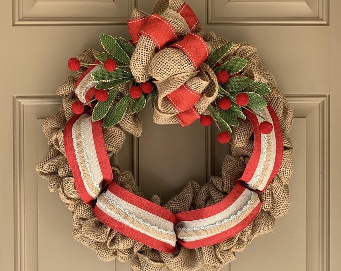 Earthy terracotta chunky knit scarf wreath resting on hallway console table with warm sconce lighting