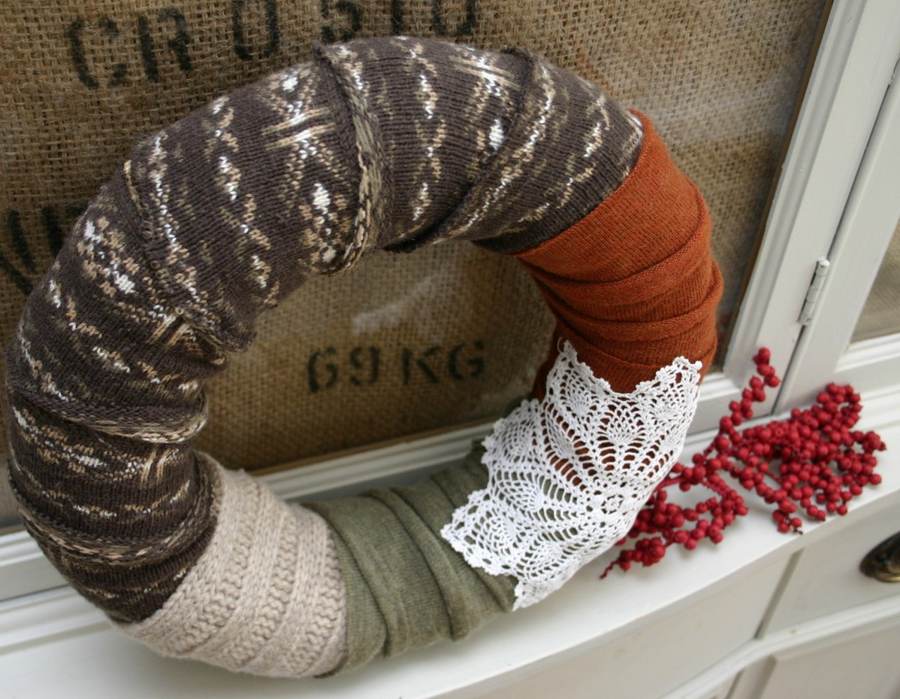 Winter entryway featuring chunky knit cream scarf wreath on wooden console with warm ambient table lamp.