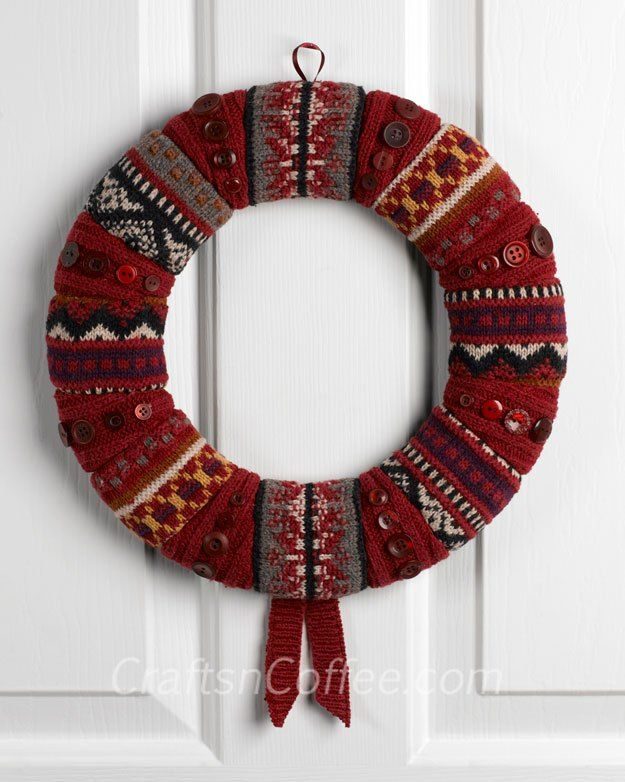 Stone fireplace hearth adorned with traditional red plaid scarf wreath suspended over rustic cedar mantlepiece.