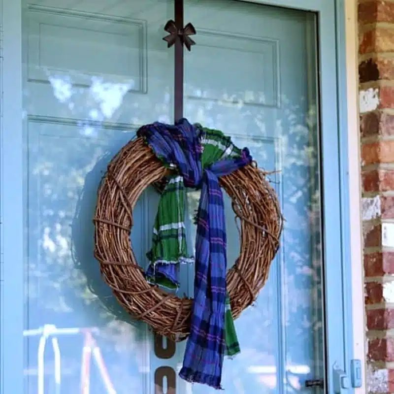Kitchen pantry door decorated with black and white buffalo check scarf wreath and rustic wooden tag.