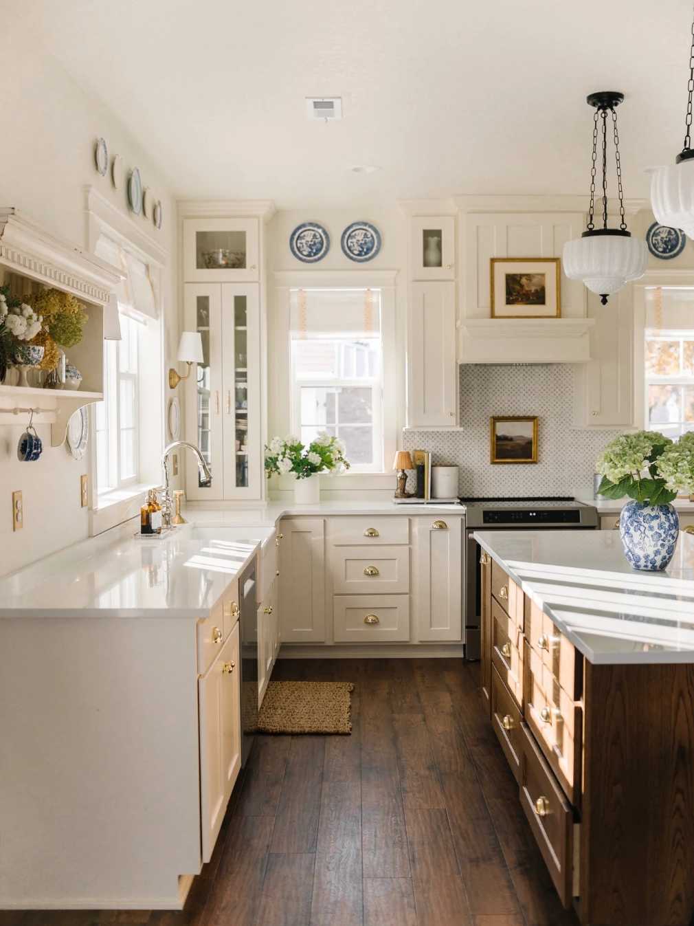 Traditional kitchen featuring cream walls, walnut cabinets, marble backsplash, crystal chandelier, brass hardware.