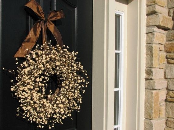 Elegant entryway with cream berry wreath tied with rich brown satin ribbon under soft lighting.