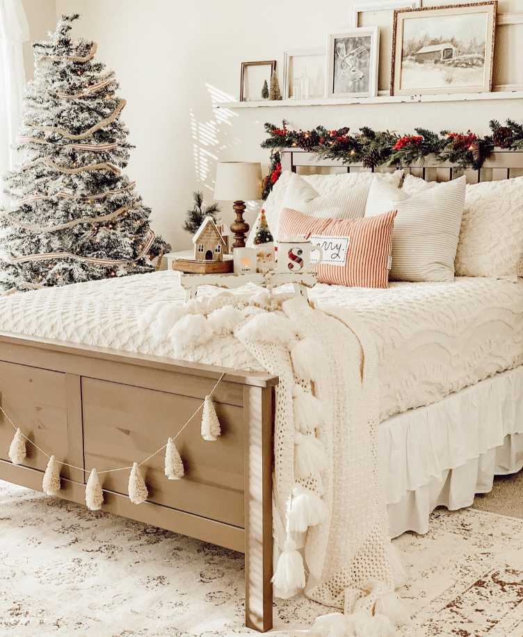 Bedroom in shades of cream and white, soft lighting, textured pillows, and minimal holiday accents.