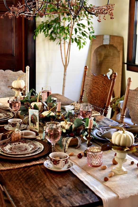 Living room dining area, mixed autumn leaves, pillar candles, amber glass vases, warm lighting