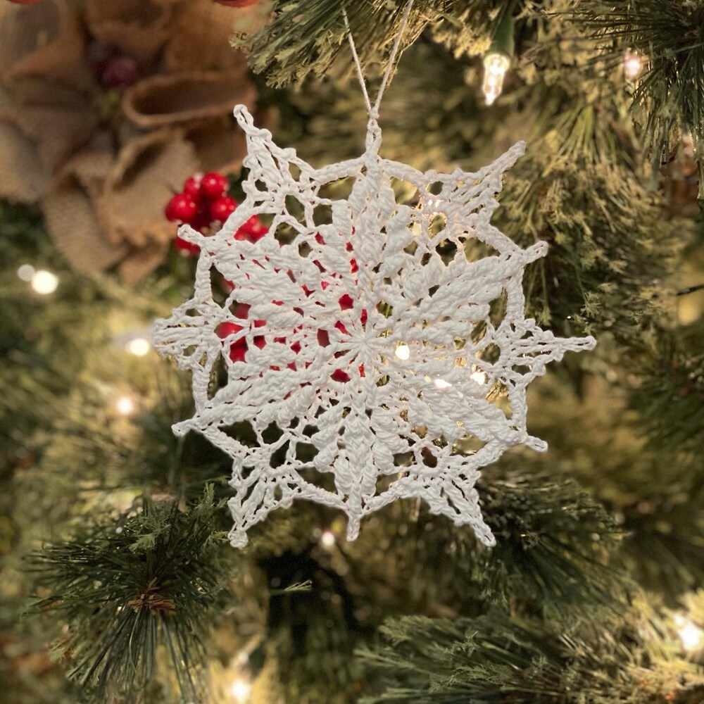 Cozy living room fireplace mantel with white crochet snowflake ornaments, warm fairy lights, and oak accents.