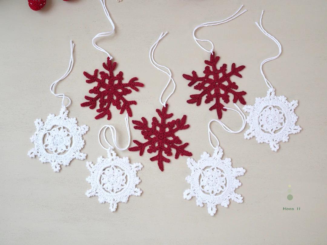 Kitchen sink window styled with red crochet heart ornaments, marble countertops, and warm under-cabinet LED lights.