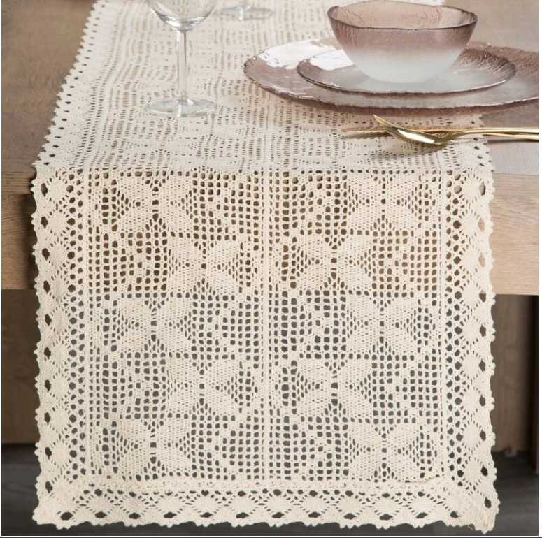 Rustic table displaying mustard yellow crochet covered mason jars glowing with warm tealight candles inside.