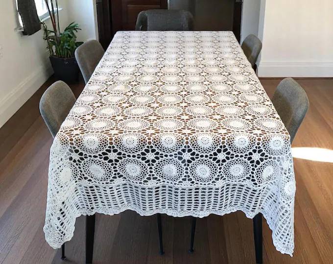 Patio coffee table with crochet table decorations, bright orange coasters, wicker furniture, natural sunlight.