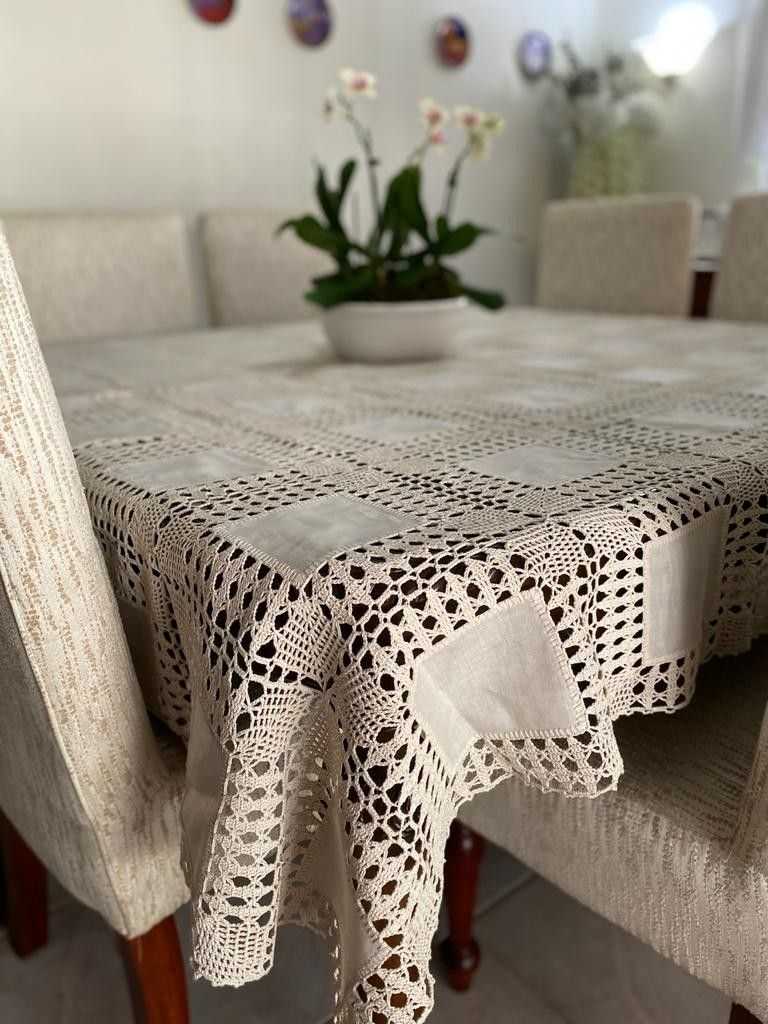 Formal dining table with crochet table decorations, metallic gold yarn, black velvet chairs, chandelier.