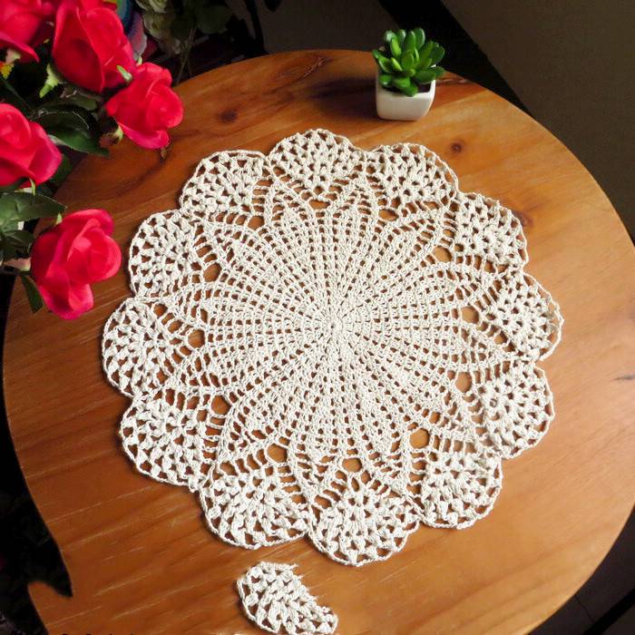 Round cafe table with pastel crochet mats, velvet chairs, floral accents, soft glow lamps.