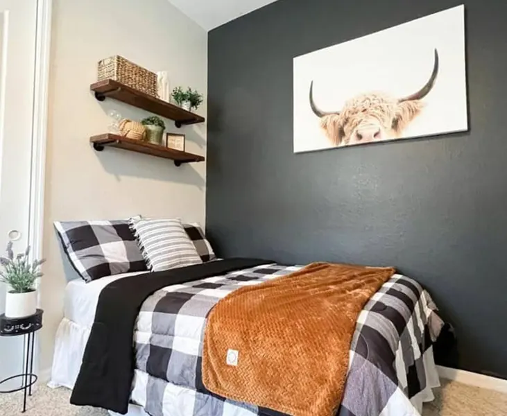 Bedroom featuring a dark accent wall, rustic wooden side table, and industrial lighting fixtures.