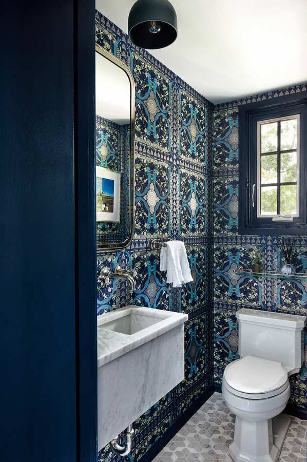 Dark blue patterned encaustic tile floor in a modern bathroom with wood vanity and warm light