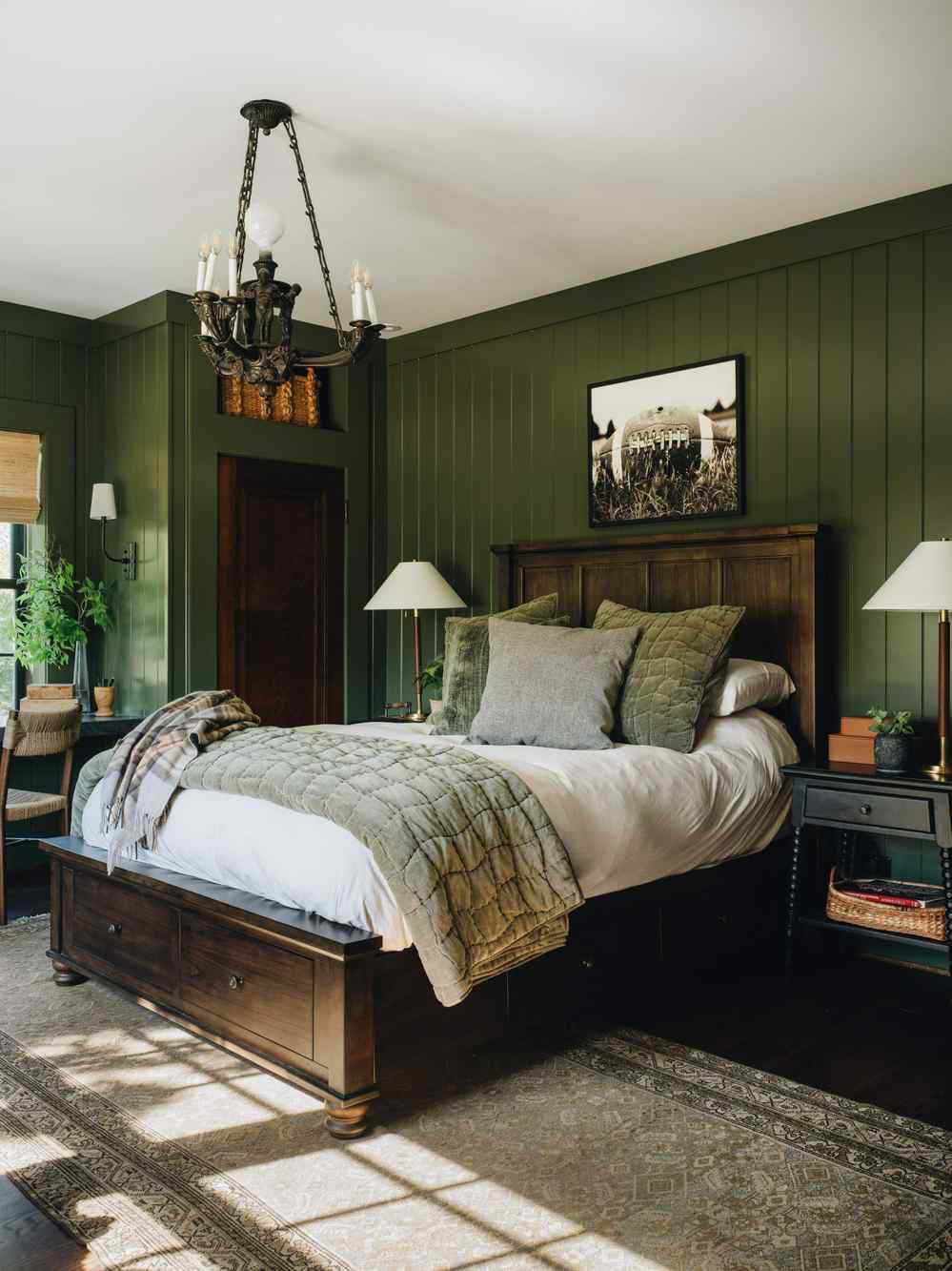 Rustic dark olive green bedroom with reclaimed timber headboard cognac leather armchair and warm bedside lamp