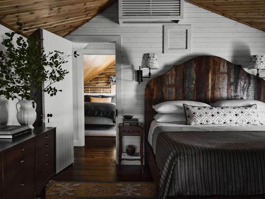 Rustic bedroom featuring a dark stained wood headboard, white shiplap walls, and amber lighting fixtures