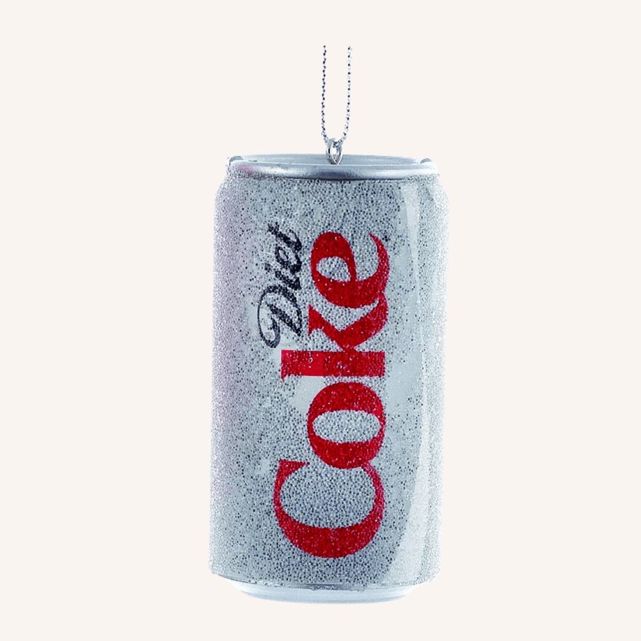 Metallic red and white Diet Coke can ornament hanging on a branch with other retro holiday decorations.