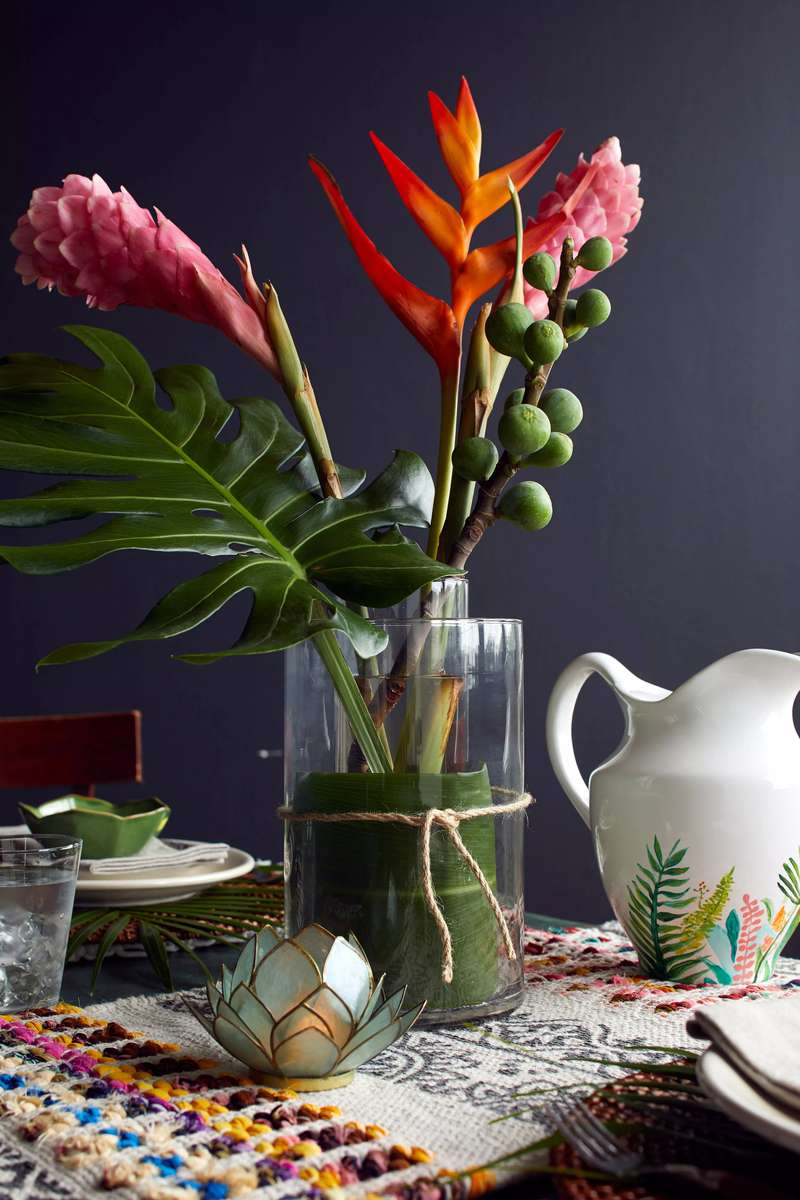 Coastal dining table with sculptural bleached driftwood branch nestled with green air plants under woven light.