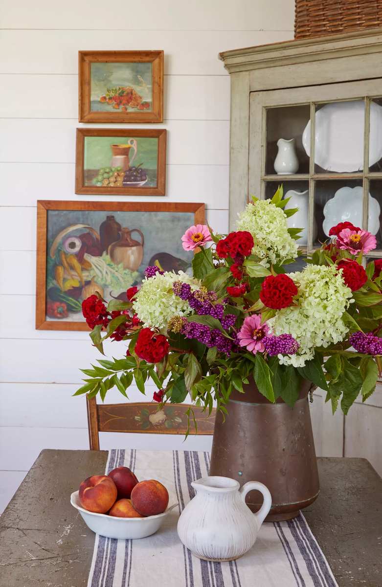 Warm bohemian dining room table displaying amber glass apothecary bottles with dried grasses in afternoon light.