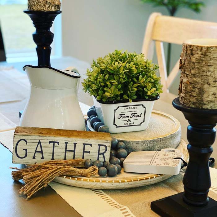 Sophisticated dining table featuring smoked gray glass hurricane candle holders, white pillars, ambient chandelier lighting.