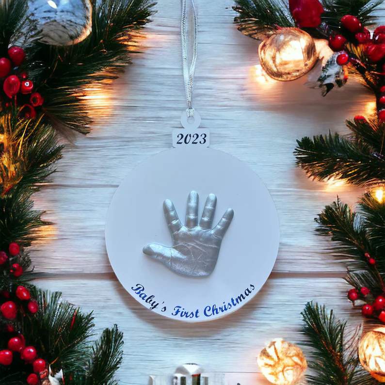 Scandinavian style living room Christmas tree featuring gold rimmed star handprint ornament with warm amber holiday lights.