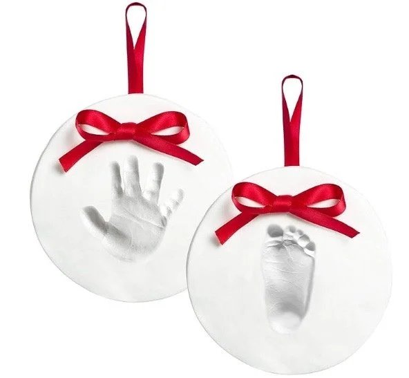 Moody atmospheric living room Christmas tree featuring metallic pewter baby handprint ornament with dark velvet backing.