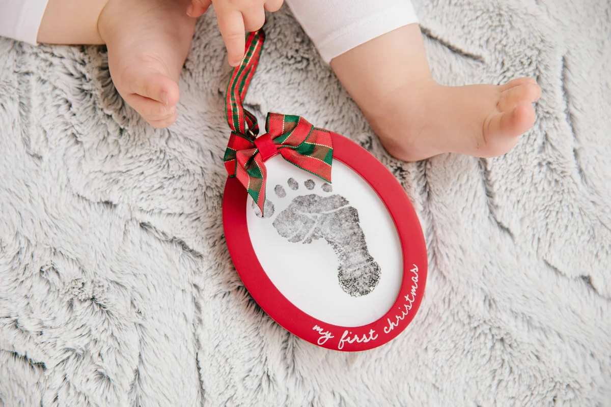 Living room mantel with rustic wood slice handprint ornament, eucalyptus garland, soft warm 2700K lighting.