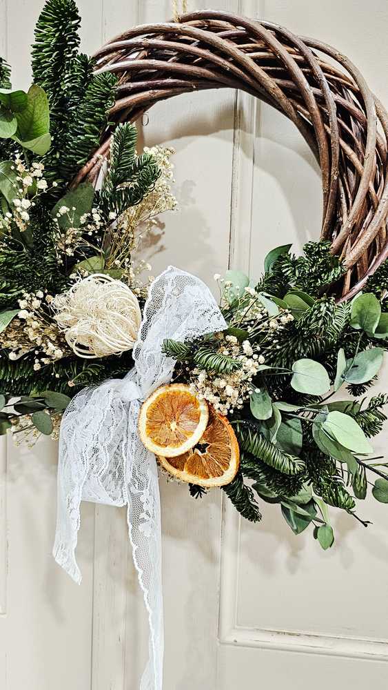 Bohemian gallery wall with dark willow wreath, fluffy cotton bolls, rattan armchair, warm directional spotlight