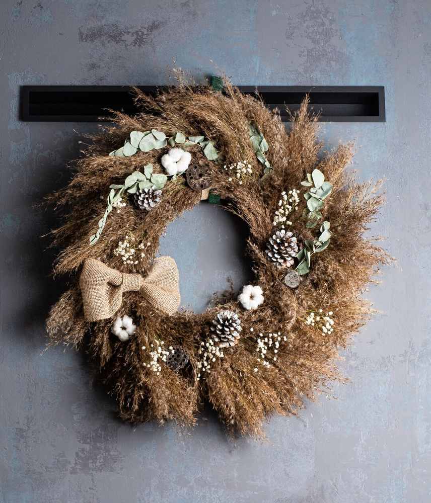 Study room with brass desk lamp, single brass hoop wreath, green sprigs, minimalist decor.