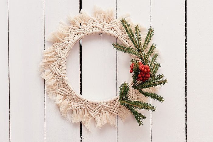 Bohemian entryway console table with rattan mirror, bleached feather wreath, brass lamp, soft warm glow.