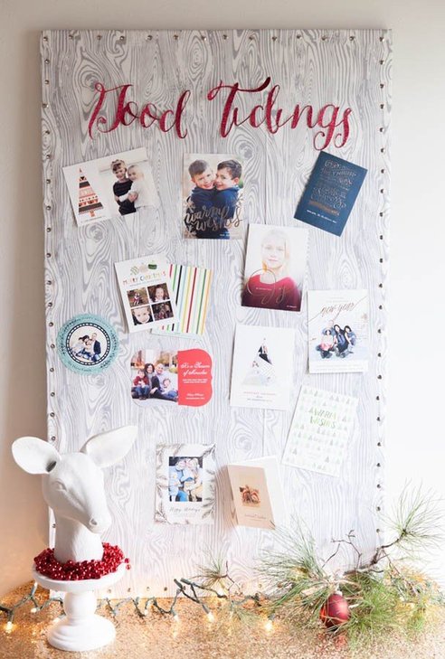 Textured linen upholstered pin board with brass studs displaying holiday cards in home office