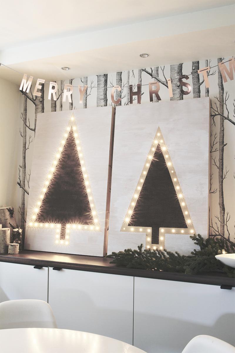 Scandinavian dining room featuring a brushed brass snowflake marquee light mounted above a light oak sideboard.