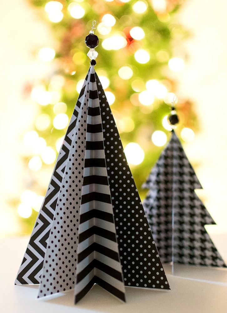 Natural evergreen Christmas tree crowned with large folded origami starburst topper, warm fairy lights, woven basket base.