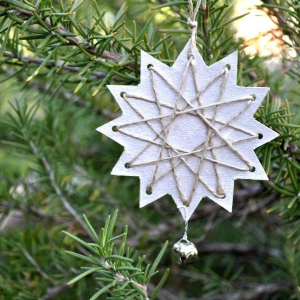 Close up of Christmas tree branch decorated with origami diamond pendants, boucle ribbon, warm soft focus lighting.