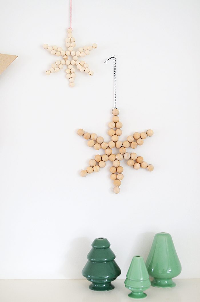 Modern farmhouse window with hanging wooden twig stars, linen drapes, and warm golden fairy lighting.
