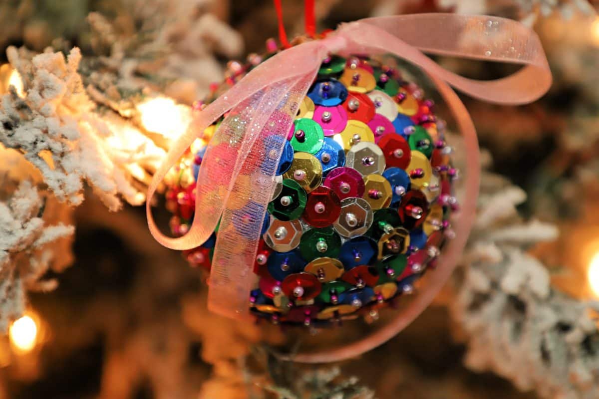 Vintage library armchair beside tree decorated with sheet music decoupage DIY Christmas tree balls warm lamps.