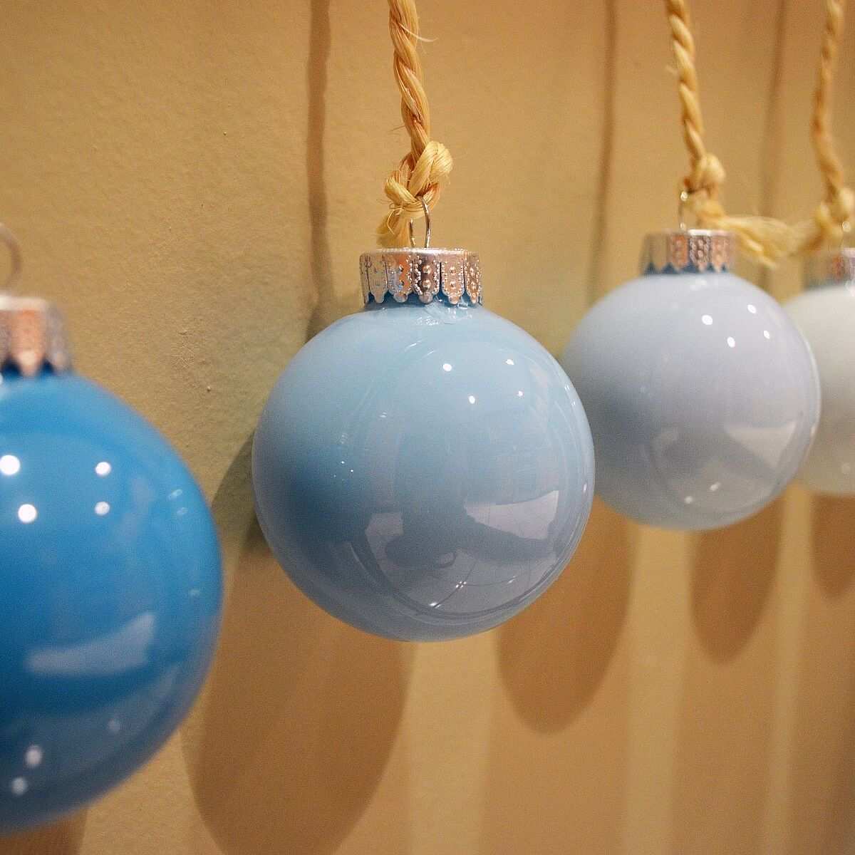 Winter living room bay window framed with icy blue diy ombre glass ornaments on silver ribbon.