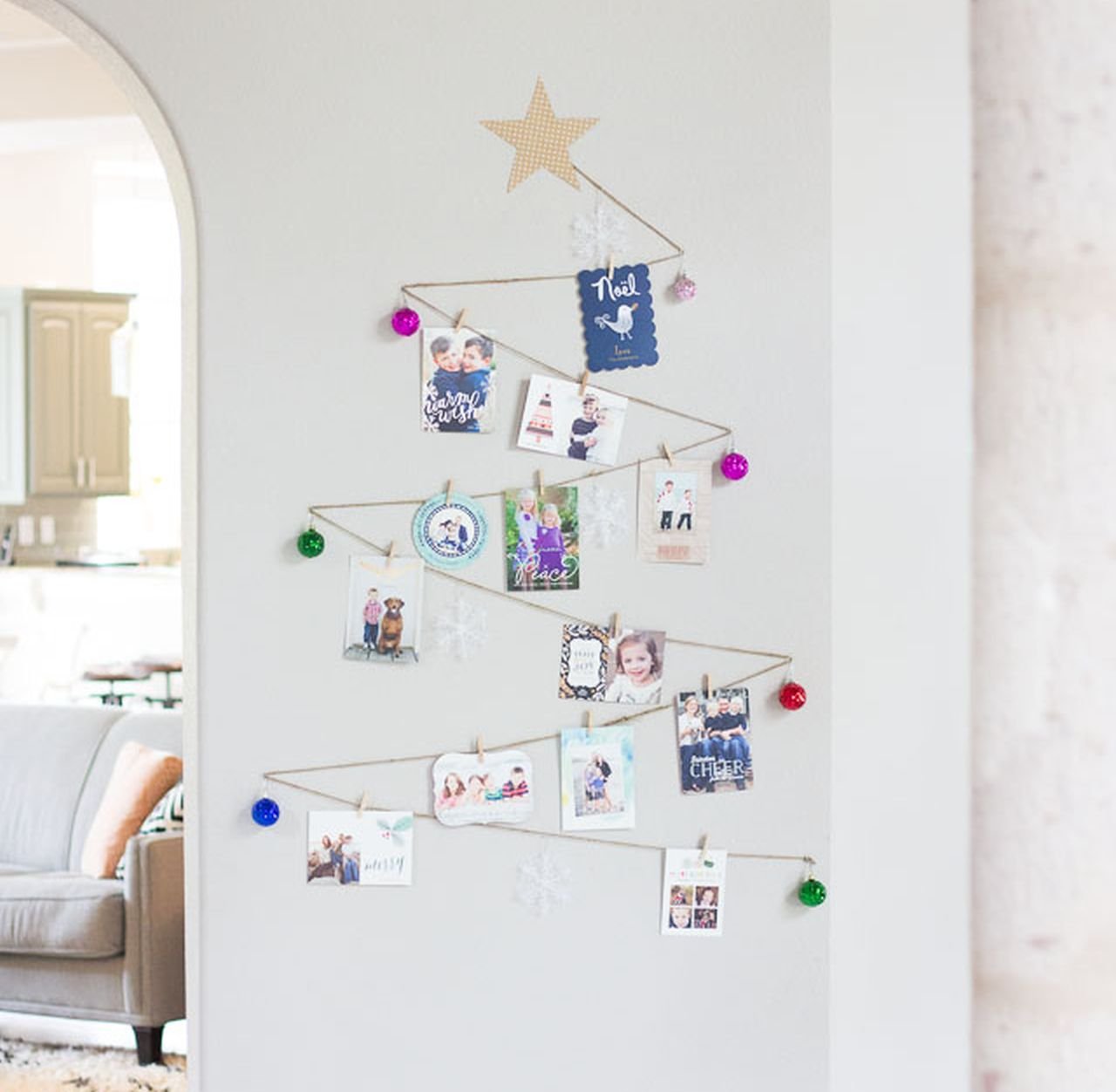 Wall mounted geometric tree silhouette made of birch dowels and lights holding holiday cards