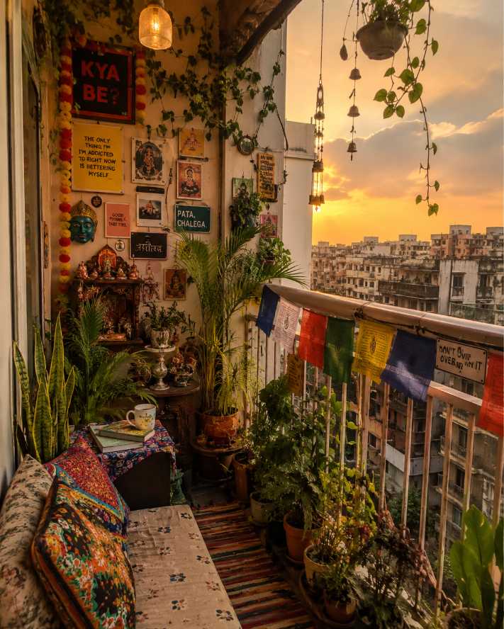Eclectic balcony with Tibetan prayer flags, vibrant textiles, and a sunset backdrop.