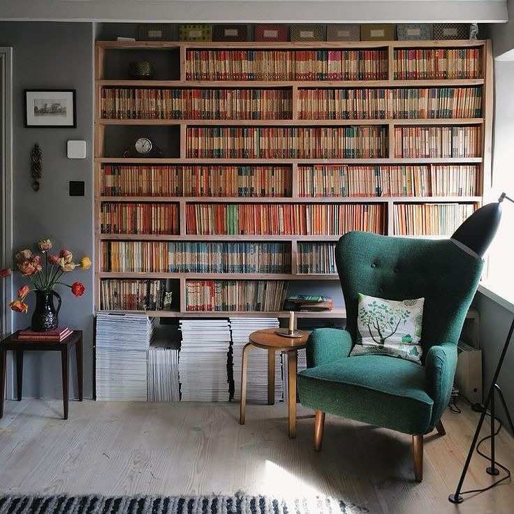 Emerald wingback armchair, built‑in walnut bookshelf, brass reading lamp, soft white walls.