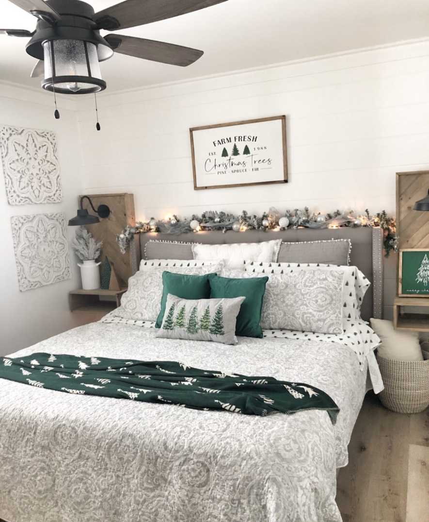 Bedroom with evergreen garlands on headboard, pine cones, deep green tones, and natural wood.