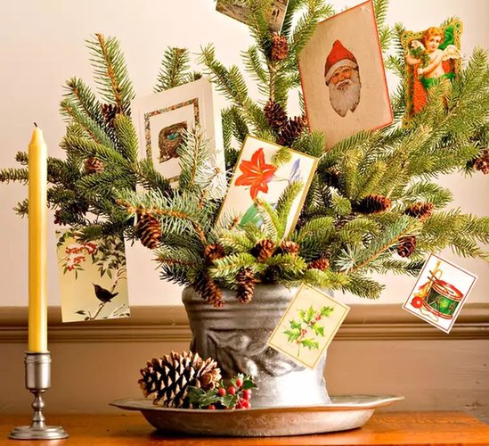 Fresh cedar and pine evergreen boughs on mantle draped with cards clipped to velvet ribbon