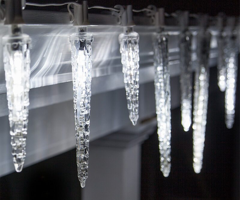 Falling rain icicle lights hung from roof eaves as modern outdoor christmas decorations.
