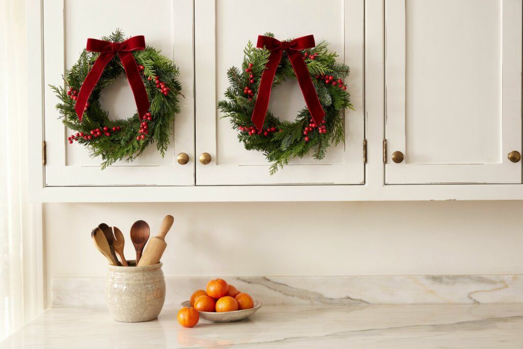 A white farmhouse kitchen island topped with a metallic silver and gold tinsel garland.