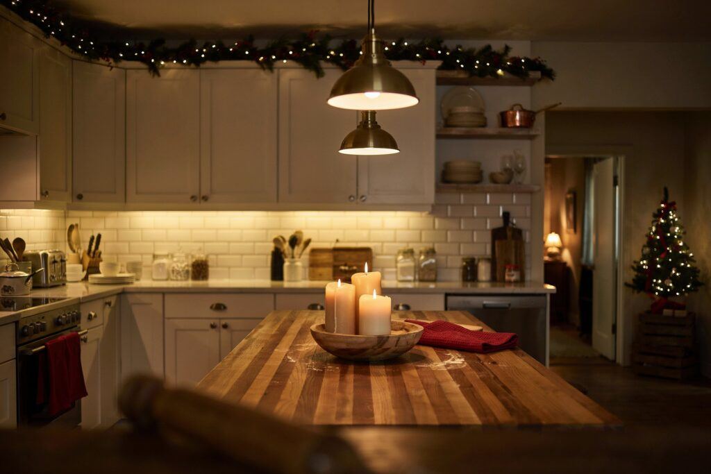 A kitchen with white countertops styled with silver ornaments and white floral arrangements.