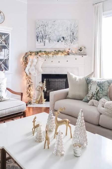 Cozy living room mantel with thick spruce garland, knit stockings, wood hearth, and warm lighting.
