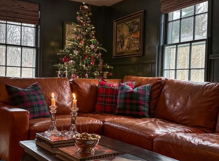 Living room fireplace mantle with plaid blankets, candle clusters, reclaimed wood hearth, amber lighting.