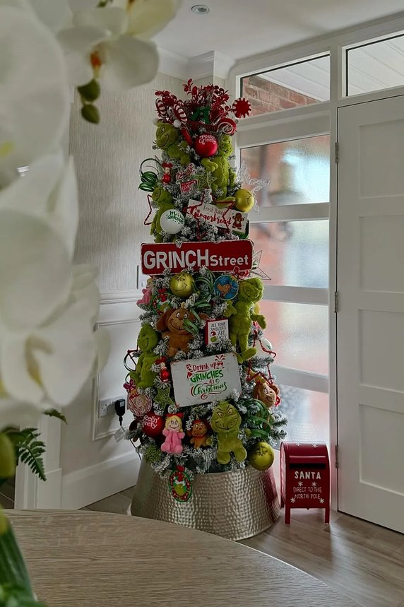 White flocked tree with green Grinch signs and warm lights in a cozy room