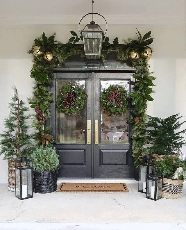 A front porch styled with forest-inspired outdoor christmas decorations like wood, pine, and lanterns.