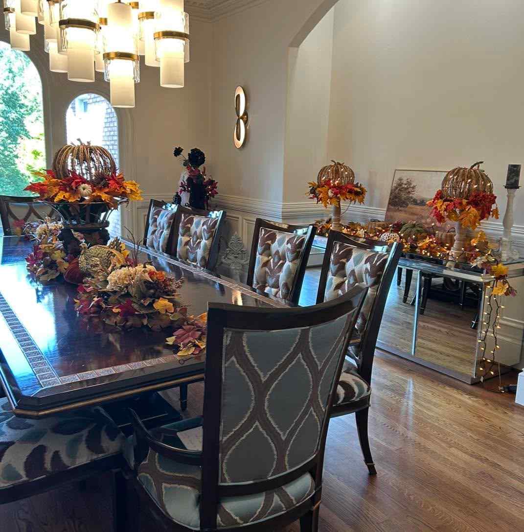 Formal dining room, wicker basket centerpiece, pumpkins, leaf garland, crystal chandelier, polished mahogany table.