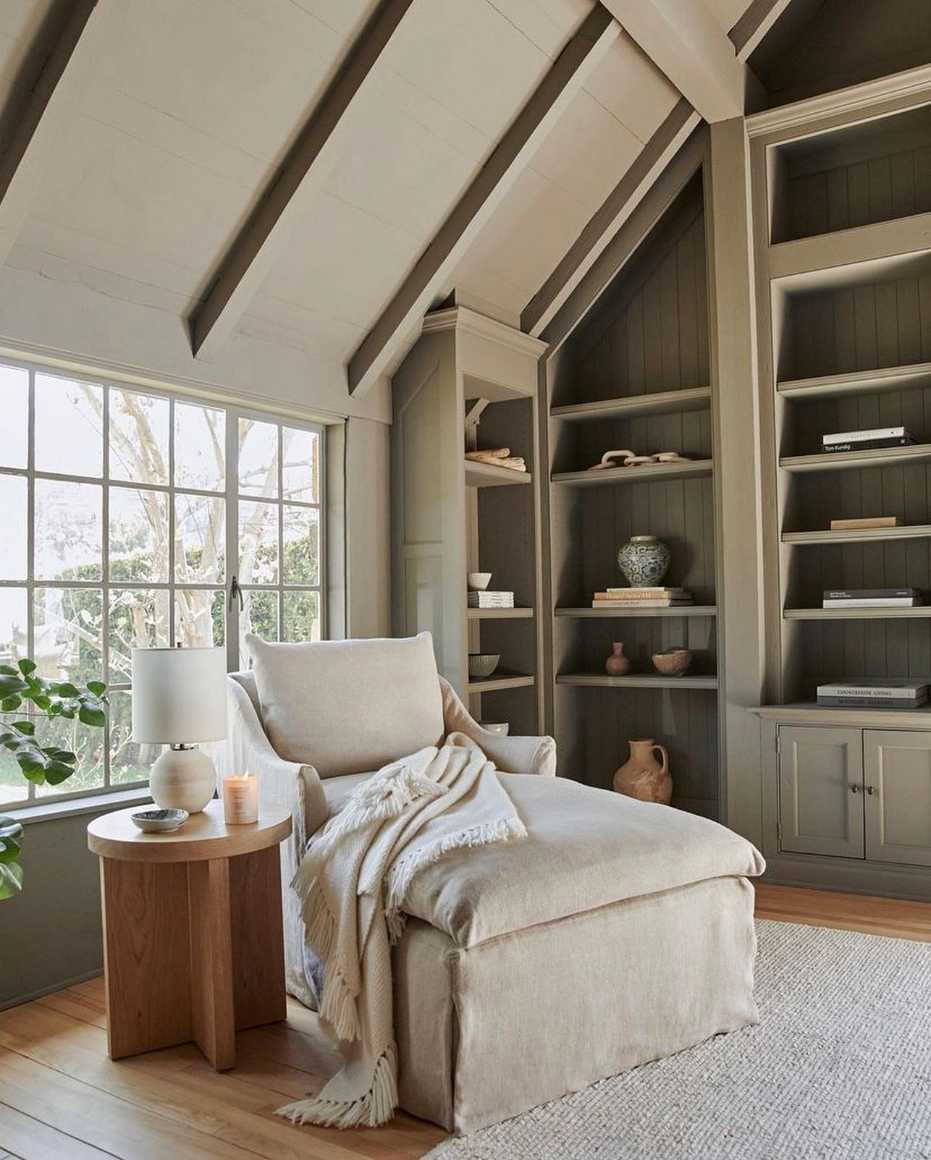 Distressed white chaise lounge, reclaimed wood side table, linen drapes, soft ivory lamp, pastel floral accents.