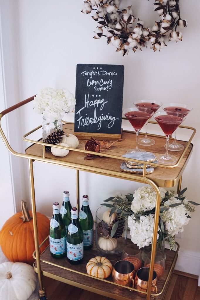 Vintage bar cart with brass handles, crystal decanters, autumn cocktail glasses, soft pendant lighting